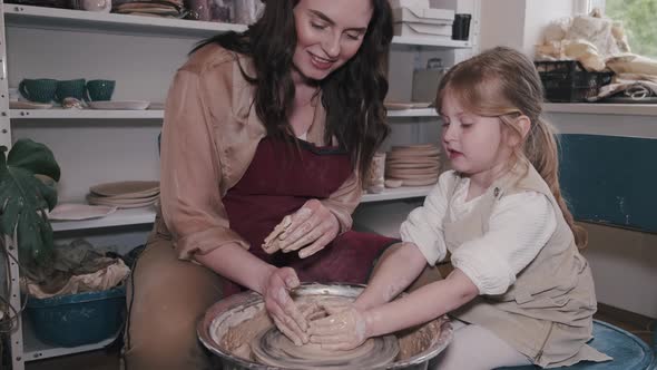 Mother with Daughter Makes Vase in a Pottery Studio alt