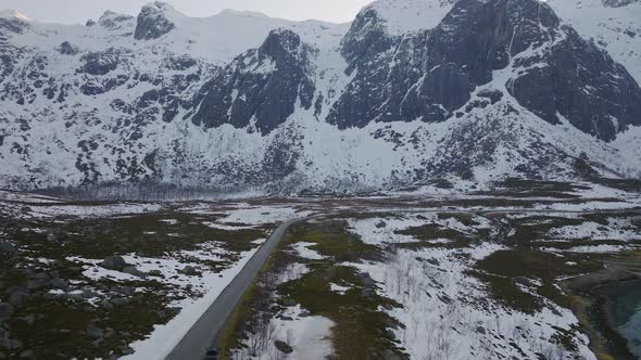 Empty road cutting through the snowy mountains in Grøtfjord. Kvaløya, northern Norway. 4K drone. alt