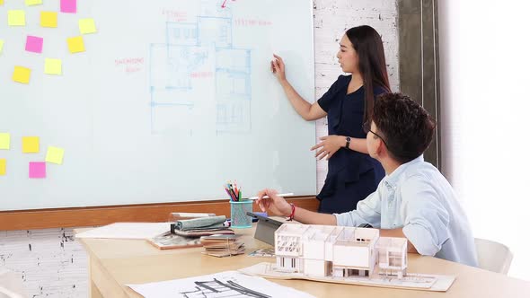 Asian  Interior Architect working with architectural model choosing material and study alt