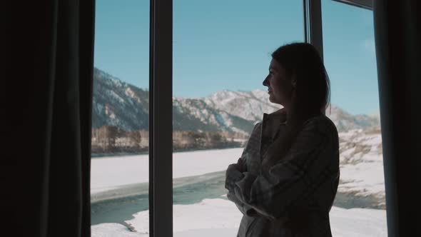 A Woman is Standing Near the Window of the House alt