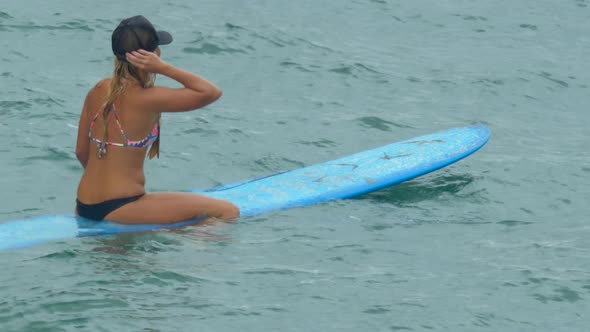 A young woman surfing in a bikini on a longboard surfboard. alt