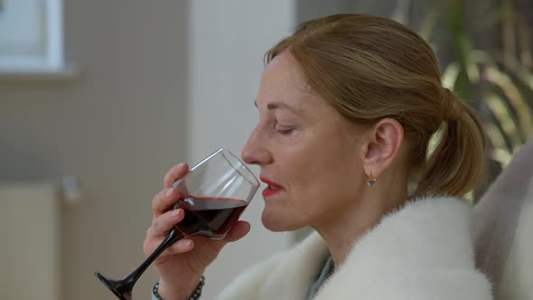 Closeup of Confident Middle Aged Elegant Woman Drinking Wine From Glass Sitting at Home Indoors alt