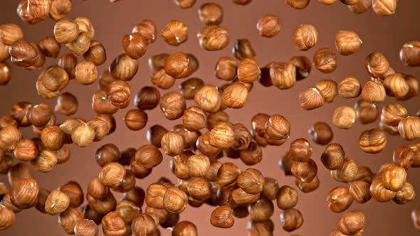 Super Slow Motion Shot of Flying Hazelnuts After Being Exploded on Brown Background at 1000 Fps alt
