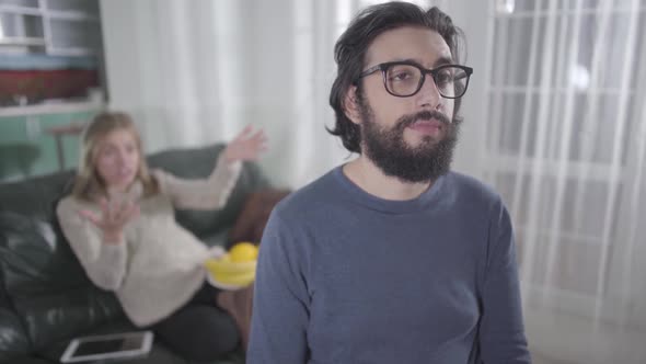 Exhausted Caucasian Man in Eyeglasses Making Faces As His Pregnant Wife Yelling at Him alt