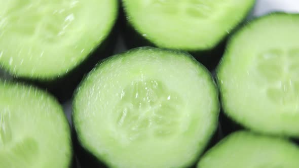 Fresh Sliced Cucumber Pieces Are Rotating on White Background Closeup View alt