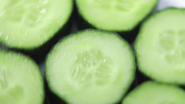 Fresh Sliced Cucumber Pieces Are Rotating on White Background Closeup View