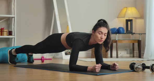 Concentrated Slim Woman Standing in Plank Position, Looking at Camera and Smiling. Portrait of alt