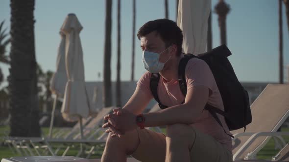 Sad Man in Protective Mask Sits on Lounger in Empty Hotel in Cyprus During Quarantine and Covid 19 alt