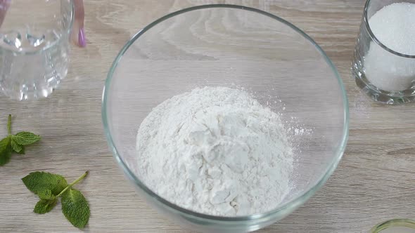 Female hands adding flour, sugar and salt for making dough in bowl, bakery alt