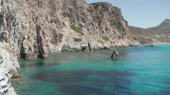 Slow Dolly Aerial in Between Rock Fomations in Turquoise Blue Ocean Water on Greek Island Milos alt