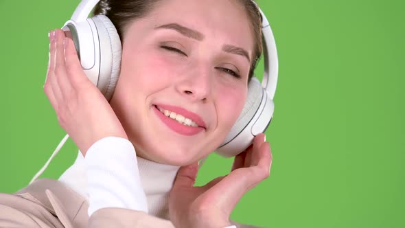 Girl Listens To Melodious Songs in the Headphones. Green Screen. Close Up alt