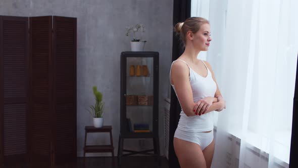 Young  girl is standing in front of the window alt