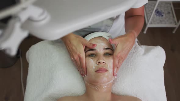 Caucasian woman lying back while beautician gives her a facial alt