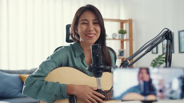 Asia girl influencer play guitar music use microphone record with smartphone for online audience. alt