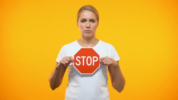 Caucasian Female Holding Stop Sign in Hands, Restriction Symbol, Warning Danger alt