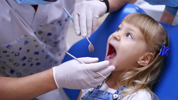 Little child in stomatology chair - close up. Cute blonde girl opened her mouth for teeth check up.  alt