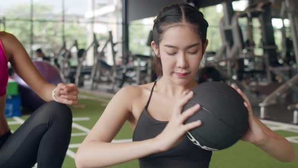 Asian lady personal trainer focus on body weight training with fitness ball to lady customer.