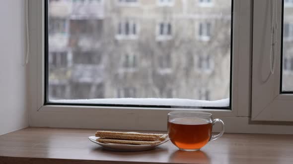 A Large Mug of Tea and Diet Bread in a Plate on the Windowsill in Winter