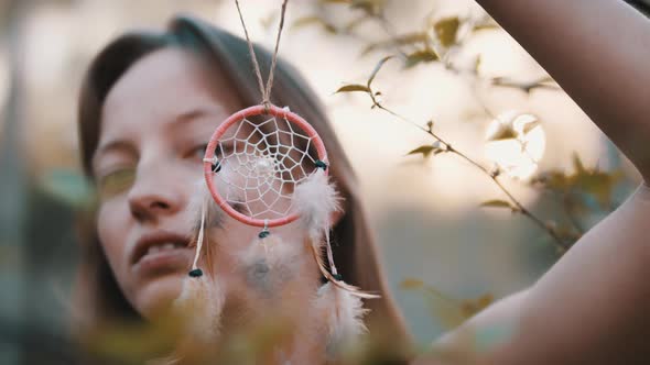 Portrait of a Young Woman Holding the Dreamcatcher in Front of Her Face. Close Up. Spirituality and alt
