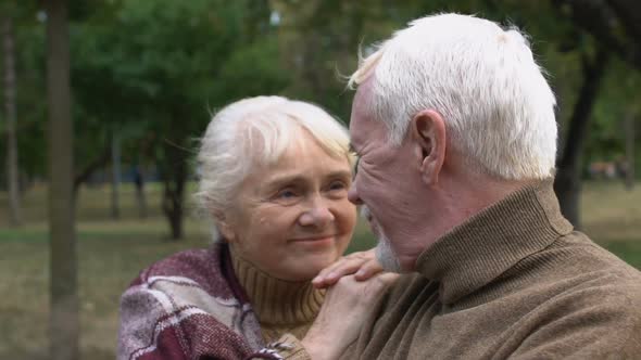 Senior Man and Woman Admiring Each Other Sitting on Bench in Park, Close-Up