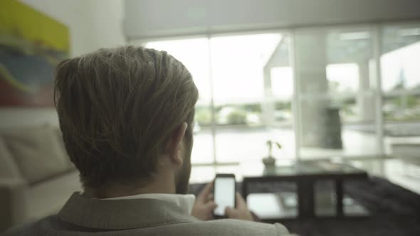 Man text messaging with smartphone in waiting room alt