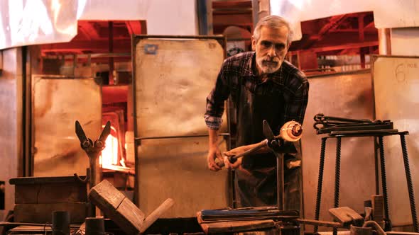 Glassblower shaping a molten glass alt