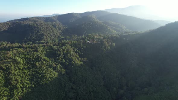 Aerial landscape view of the sun is shining through the greenery rainforest mountains by drone