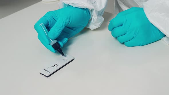 doctor transfer drops of liquid sample to test cassette of Coronavirus Antigen Rapid Test kit (ATK)