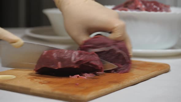 Cutting of Meat of Wild Elk. Dark Raw Meat Processing. Cutting on a Wooden Cutting Board. alt