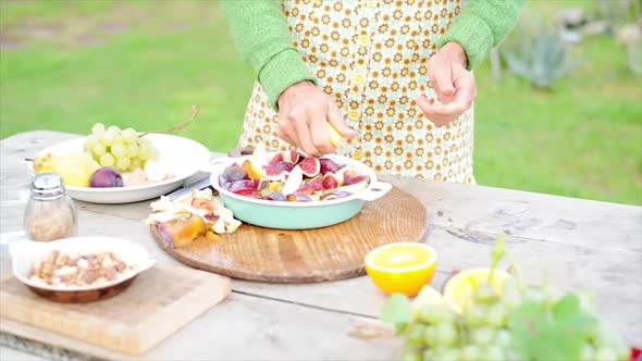 Woman squeezing citrus over cut-up fruits alt