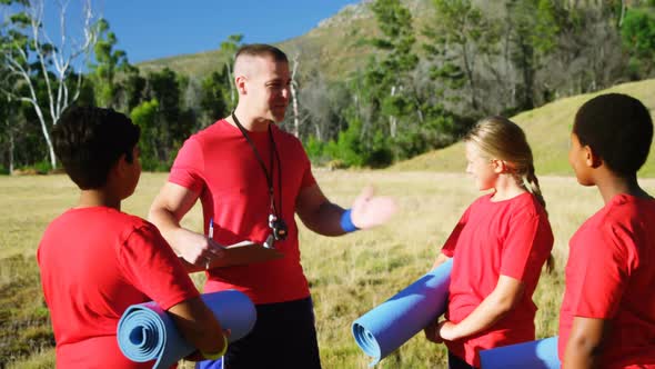 Male trainer interacting with kids in the boot camp 4k