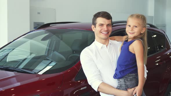 Dad and Daughter on His Hands Stand on the Background of the Car