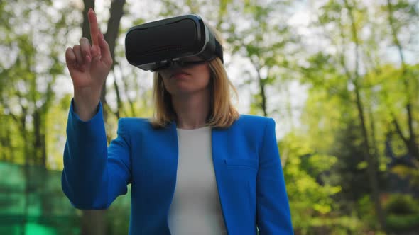 Business Woman Controls the Virtual Interface By Pressing Buttons with Her Finger in VR Goggles alt