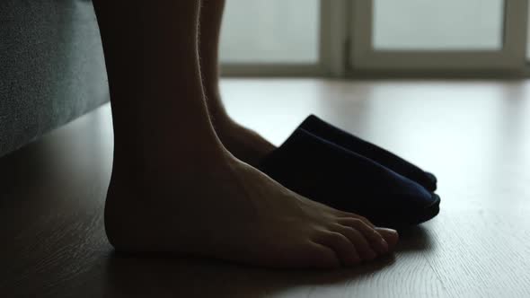 Silhouette of young adult man legs slips a slippers