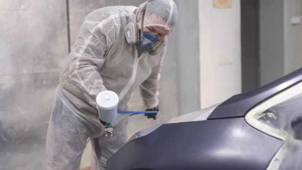Auto Painter Spraying Black Paint on Car Wing in Special Booth