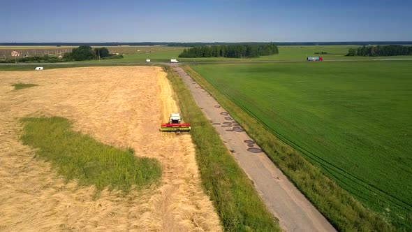 Aerial Motion Above Harvesting Combine and People on Field alt