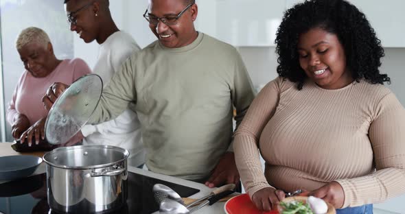 Happy black family having fun cooking together inside kitchen at home alt