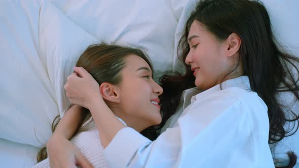 Asian beautiful lesbian couple lying down on bed and hugging each other. Homosexual-LGBTQ concept alt