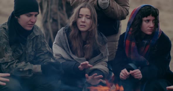 Soldier With Refugees Warming Hands At Bonfire alt
