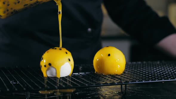 Closeup of a Pouring Yellow Glazing Over Ball Desserts in Slow Motion
