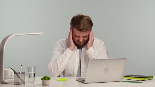Tired Young Man Working on Laptop at Home Office and Suffering From Migraines alt