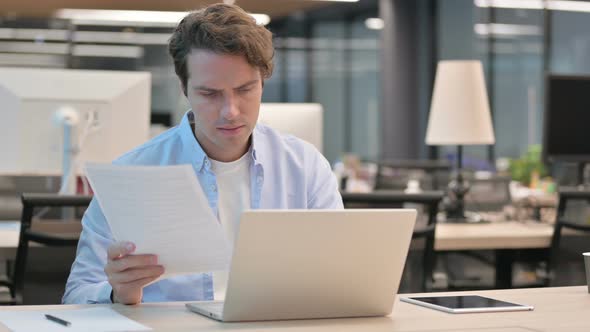 Frustrated Man REacting to Loss While Reading Documents alt