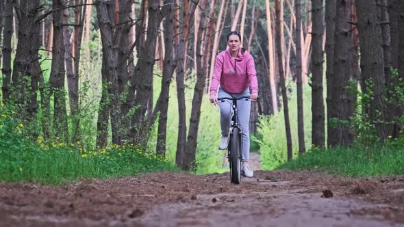 Young Woman on a Bicycle Rides Along a Forest Path in Summer Day Slow Motion alt