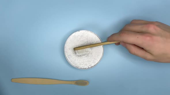 The dental powder applies to a wooden toothbrush. Gently blue background