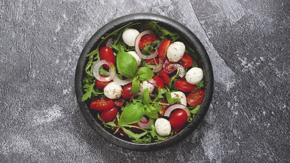 Salad with Traditional Italian Mozzarella Cheese with Arugula and Tomatoes on Dark Concrete Table