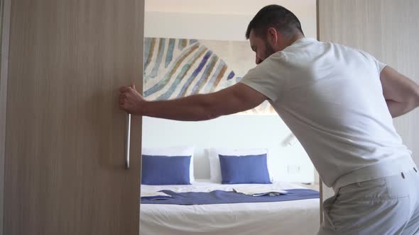 Men with Outstretched Arms Lies on His Back on the Hotel Room Bed
