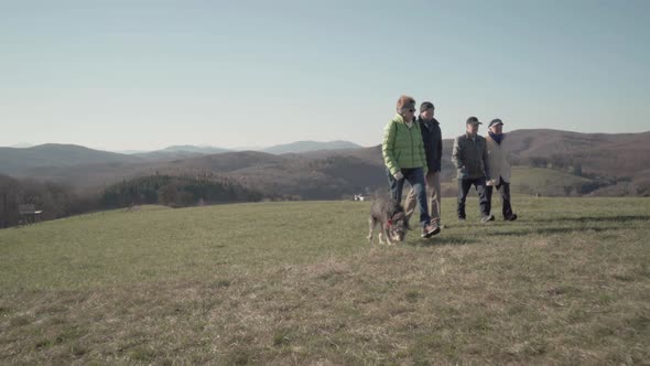 Four Active Seniors Walking Over Meadow to Bench alt