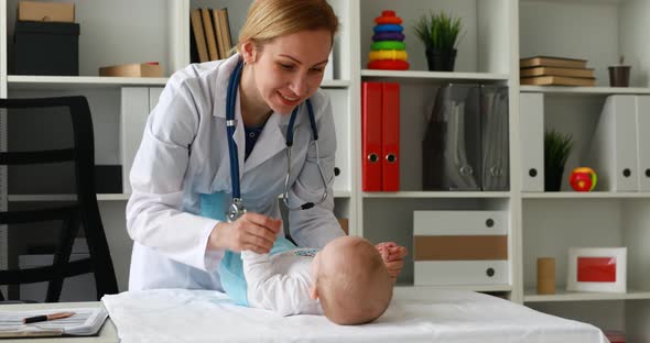 Pediatrician Kneading Child Hands Lying on Table