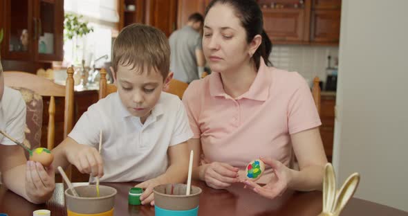 Mom Helps Her Sons Paint Easter Eggs alt