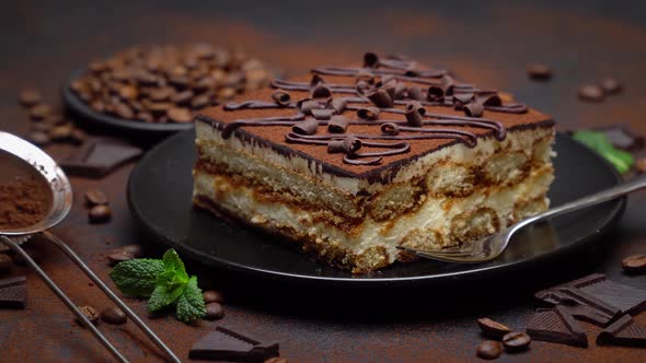 Portion of Traditional Italian Tiramisu dessert and pieces of chocolate bar alt
